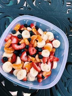 a plastic container filled with sliced fruit on top of a metal tablecloth covered bench