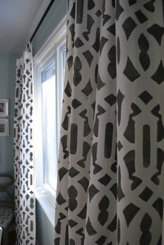 the curtains in this bathroom are drawn with black and white designs on them, while the window is open