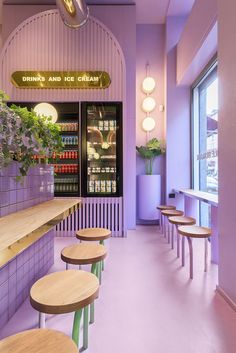 the interior of a restaurant with purple walls and wooden tables in front of it, along with potted plants