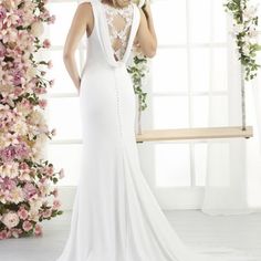 a woman in a white wedding dress standing next to flowers