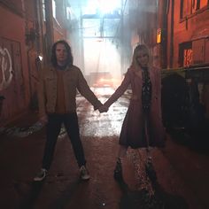 two people holding hands while standing in an alley