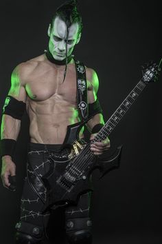 a man with green paint on his face holding a guitar