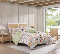 a bed in a room with wooden floors and white walls, along with a flowered comforter