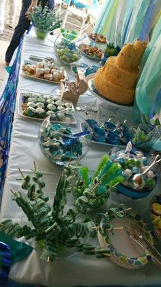 a table filled with plates and desserts on top of a blue cloth covered table