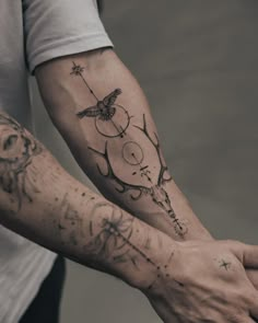 two people holding hands with tattoos on their arms and arm, one has a bird in the middle