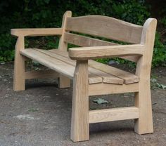 a wooden bench sitting on top of a cement ground next to green bushes and trees