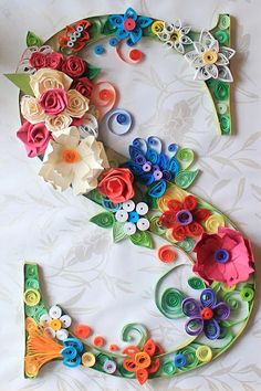 the letter e is made up of paper flowers and other colorful things to decorate it