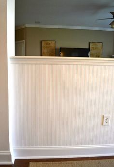 an empty room with a ceiling fan in the corner and white paneling on the walls