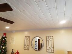 a living room filled with furniture and a christmas tree in front of a ceiling fan