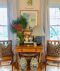 two vases sitting on top of a wooden table next to a lamp and pictures