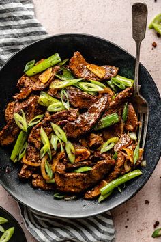 beef and asparagus stir fry in a skillet with a fork on the side