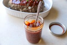 a jar filled with food sitting on top of a table next to a container of sauce