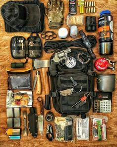 an assortment of items laid out on a wooden table to be used as a survival kit