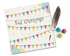 a greeting card with colorful bunting, feathers and paper beads on it next to a feather quill