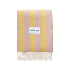 a pink and yellow striped blanket with a white tag on the bottom that says maison dux