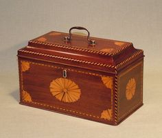 a wooden box with an intricate design on it's lid and handle, sitting on a white surface