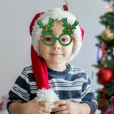 a young boy wearing glasses and a santa hat