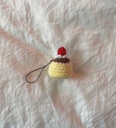 a small crocheted cupcake with a red hat on it's head