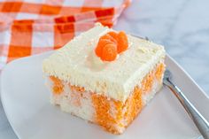 a piece of carrot cake on a plate with a fork and orange checkered napkin