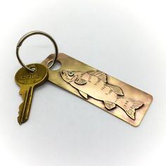 a key chain with a fish engraved on it and two keys attached to the back