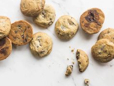 chocolate chip cookies on a marble counter top with one broken in half and the other uncooked