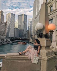 a woman sitting on the edge of a bridge looking at her cell phone