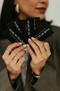 a woman holding four business cards in her hands