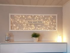 a white shelf with lights on it and a plant in the corner next to it