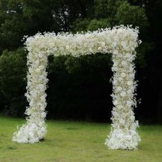 an outdoor wedding ceremony setup with white flowers on the arch and greenery in the background