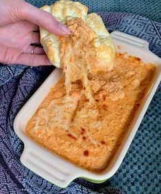 a person is grabbing some food out of a casserole dish on a blanket