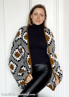 a woman is posing for a photo in front of a white door wearing a black turtle neck sweater and leather leggings