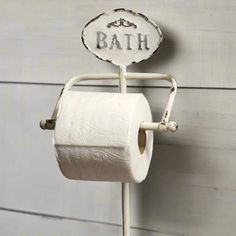 a white toilet paper holder with a personalized sign on it and two rolls of toilet paper