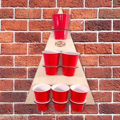 red cups are lined up on a shelf in front of a brick wall