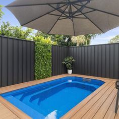 an outdoor pool with wooden decking and umbrella