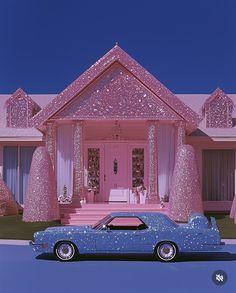 a blue car parked in front of a pink house with glitter decorations on the roof