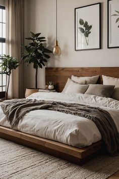 a large bed sitting in a bedroom next to a window with plants on the wall