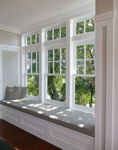 the sun shines through three large windows in a white room with wood flooring