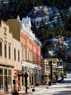 an old town with snow on the mountains behind it