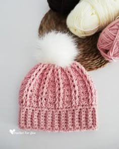 three balls of yarn and a knitted hat on a white table with knitting needles