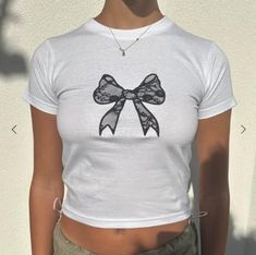 white baby tee with black lace bow 100% cotton Model is wearing size S and is a 6/8 - For reference, model is 5'5 with 31" bust and 26" waist Spring Cotton T-shirt With Bow, Casual Cotton T-shirt With Lace Trim, White Crew Neck T-shirt With Lace Trim, Short Sleeve Cotton T-shirt With Lace Trim, Spring Cotton T-shirt With Lace Trim, Cotton Crew Neck Top With Bow Print, Cotton T-shirt With Lace Trim, Cotton T-shirt With Lace Trim And Short Sleeves, Cotton T-shirt With Lace Trim, Short Sleeve