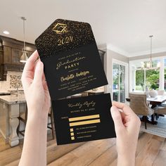 a person holding up a black and gold party card in front of a dining room table