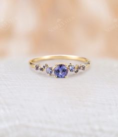 three stone ring in yellow gold with blue sapphires on the sides and diamond accents