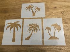 four pieces of paper cut out of palm trees on a wooden table with wood flooring