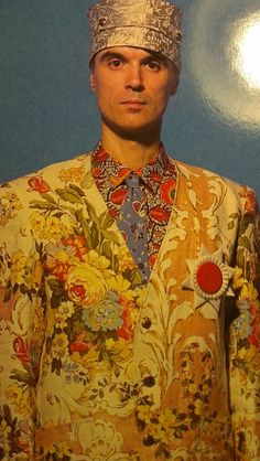 a man with a hat on top of his head standing in front of a blue wall