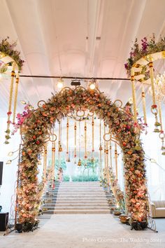 an elaborate floral archway with chandeliers and flowers on the stairs for a wedding ceremony