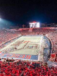 a football stadium filled with fans and cheerleaders on the sidelines at night