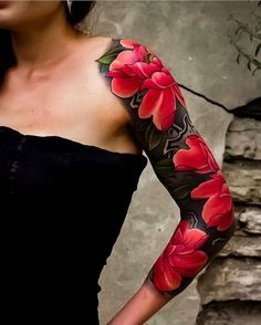 a woman wearing a black dress with red flowers on her arm