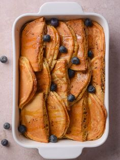 blueberry french toast in a white casserole dish with fresh blueberries on the side