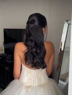 a woman in a wedding dress looking at herself in the mirror