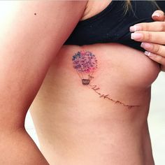 a woman with a tattoo on her stomach holding a flower in the shape of a balloon